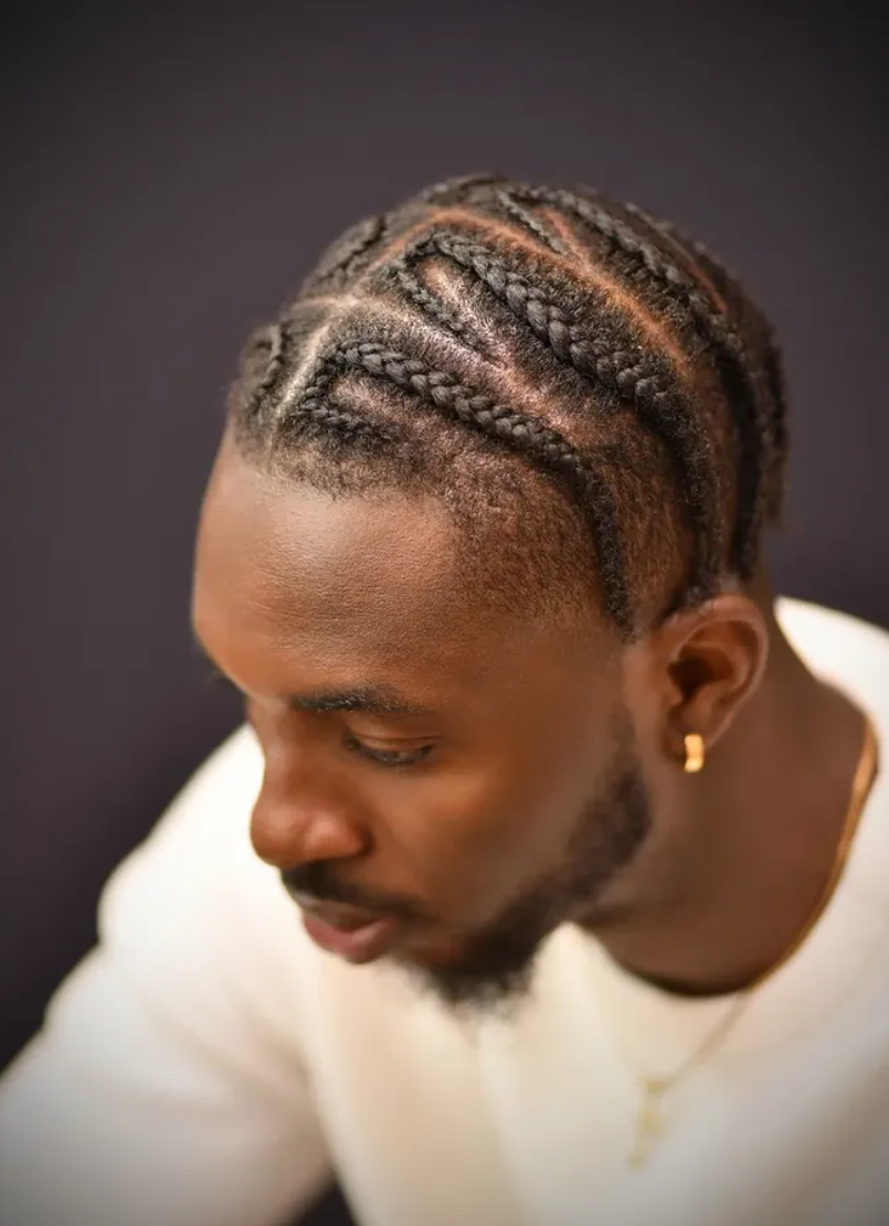 Close portrait of a man with braided hair, looking down