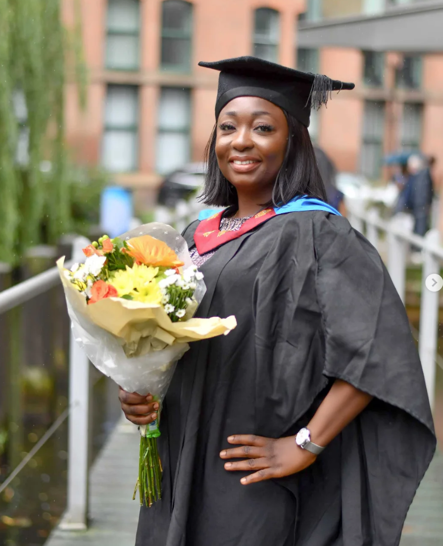 Graduate in cap and gown holding a bouquet of flowers