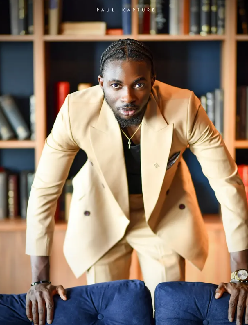 Editorial portrait of a man in a cream double-breasted suit in a library