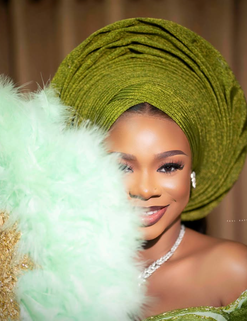 Bridal portrait of a woman in a green gele with a feather fan